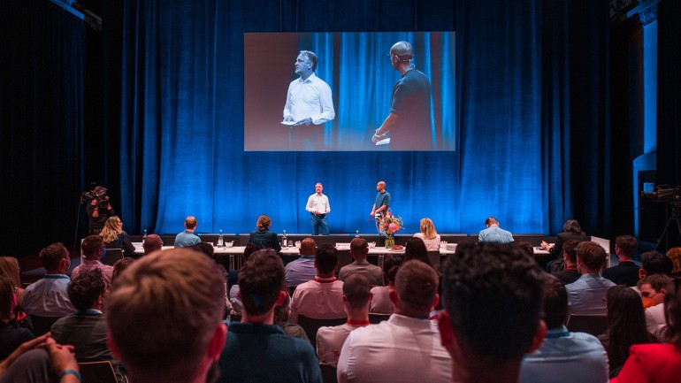 Bertelsmann lud Top-Student:innen aus ganz Europa nach Berlin ein. Personalvorstand Immanuel Hermreck und Moderator Amiaz Habtu begrüßten die Teilnehmenden zur 14. Ausgabe der Karriere-Veranstaltung ‚Talent Meets Bertelsmann‘. (© Bertelsmann)